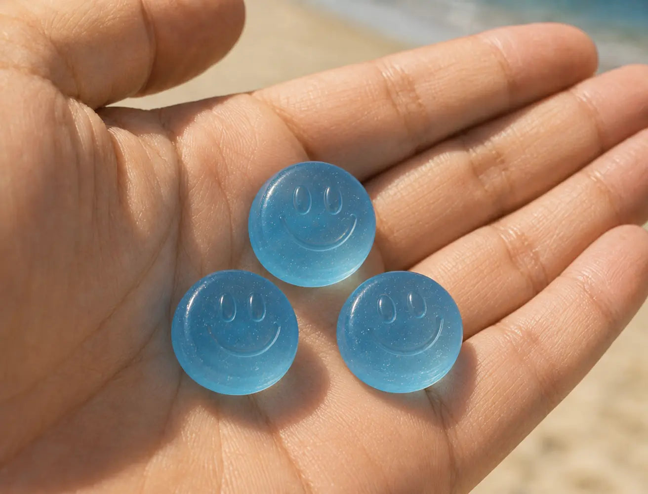Three round red Day Glow smiley gummies held in an open hand
