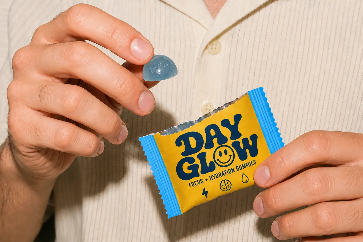 Person holding an open Day Glow packet and one red smiley gummy